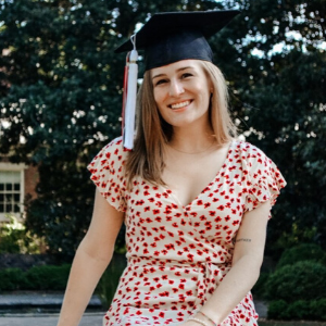 Caroline Clabby with graduation cap on sitting in front of fountain