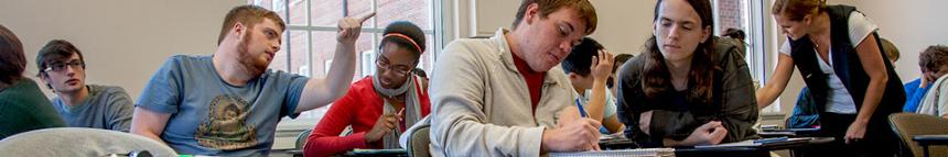 Students in a classroom discussing work together.