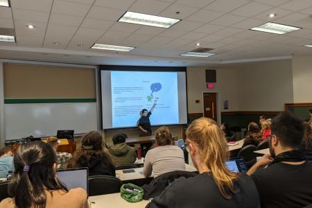 Dr. Yoshida presenting in front of classroom while attendees watch