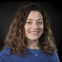 Portrait of Betsy Miller in blue shirt in front of black background